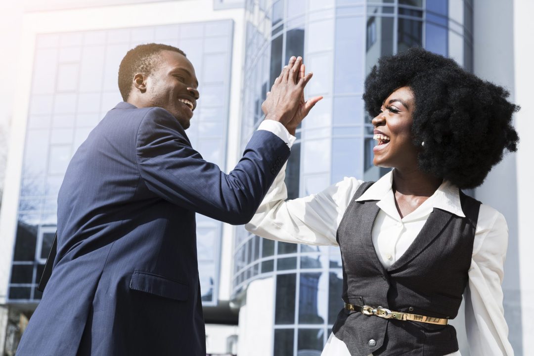smiling-young-businessman-businesswoman-giving-high-five-front-corporate-building